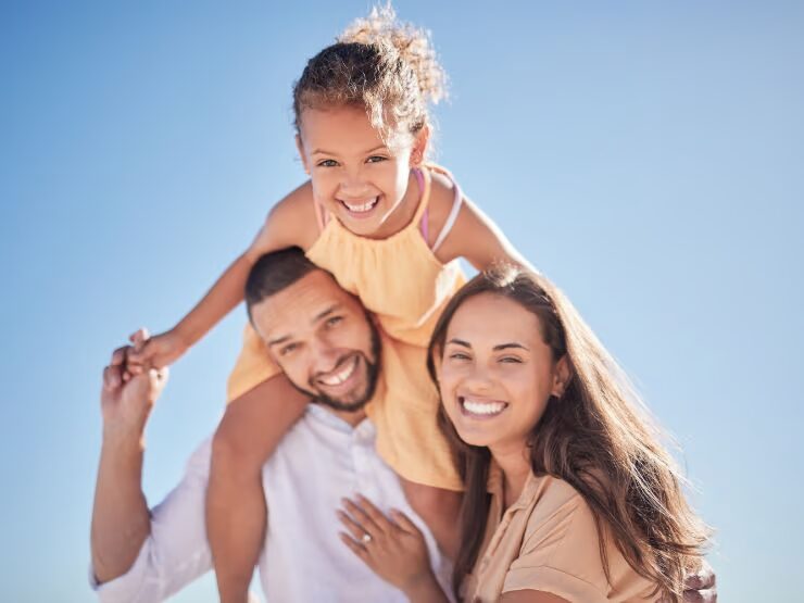 Um pai, uma mãe e uma criança, abraçados, traduzindo em imagem o significado de tomar os pais